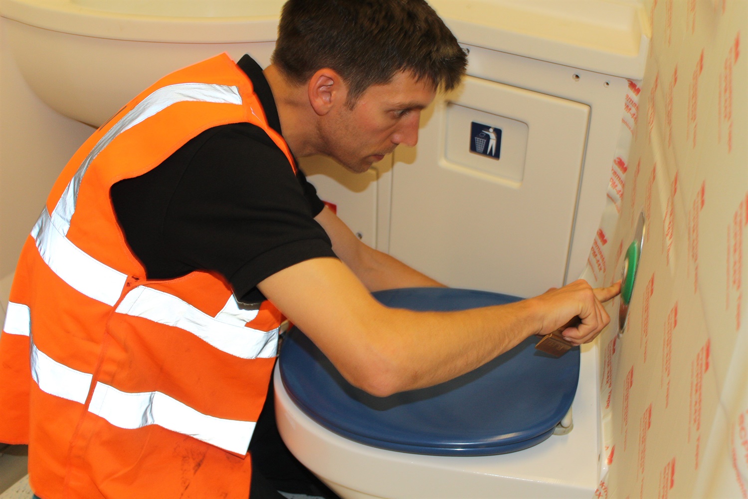 Worker refurbishing and putting screen prints on Class 375 train toilet