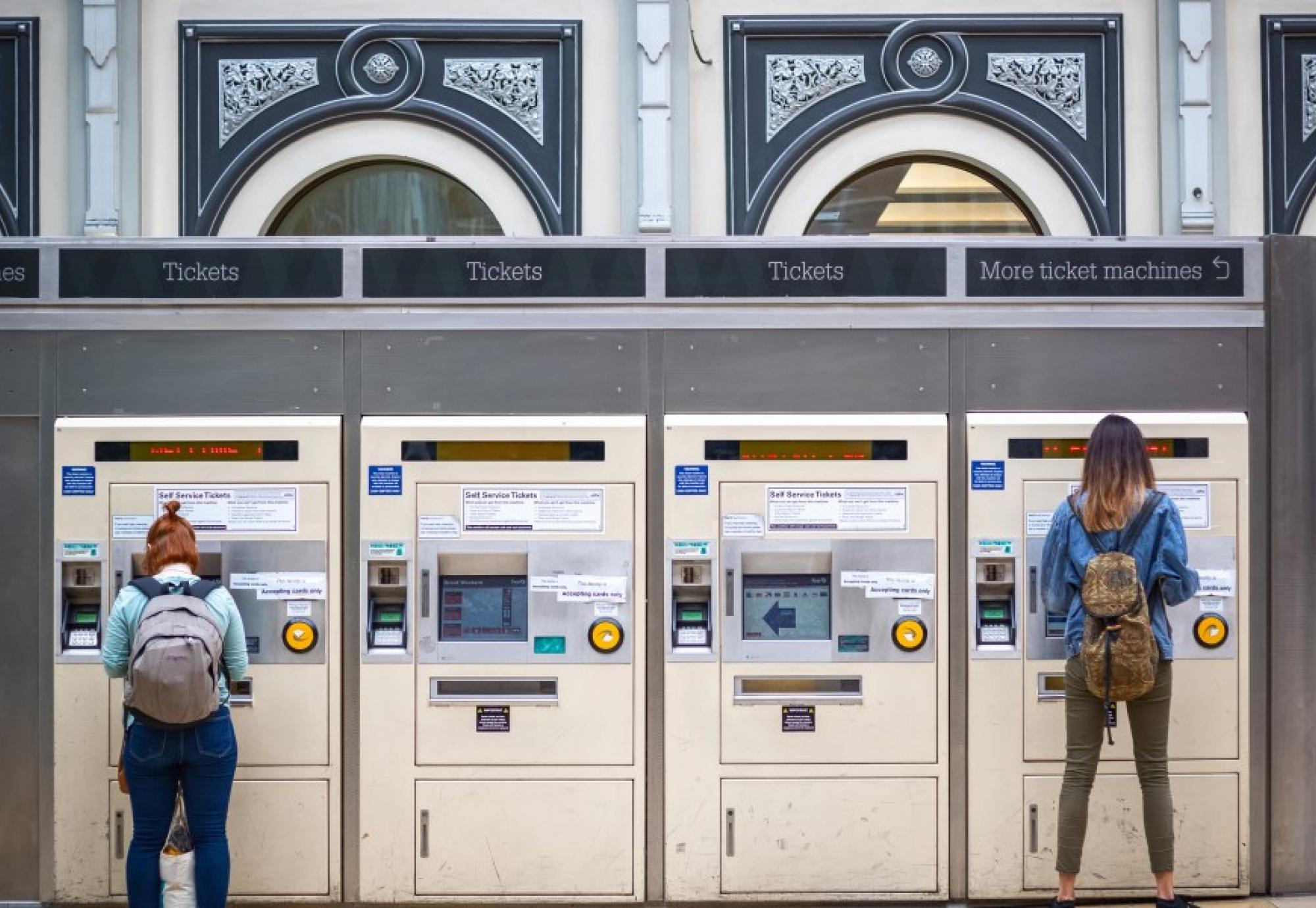 Two people buying train tickets 