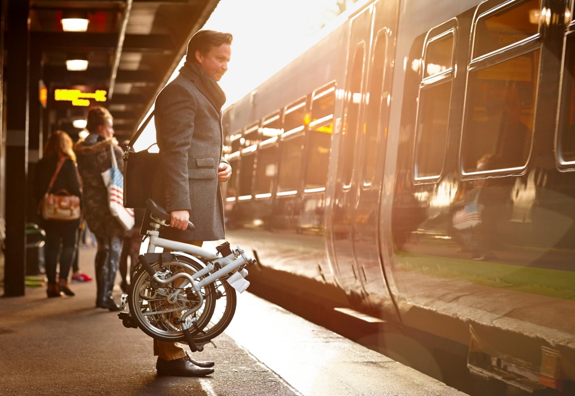 Businessman with a fold up bike at a train station