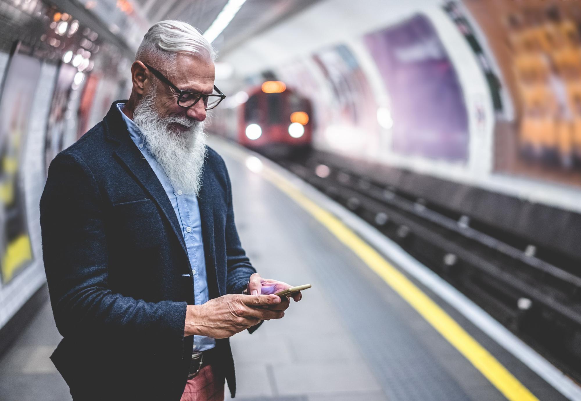 Male rail passenger at a station using a smartphone