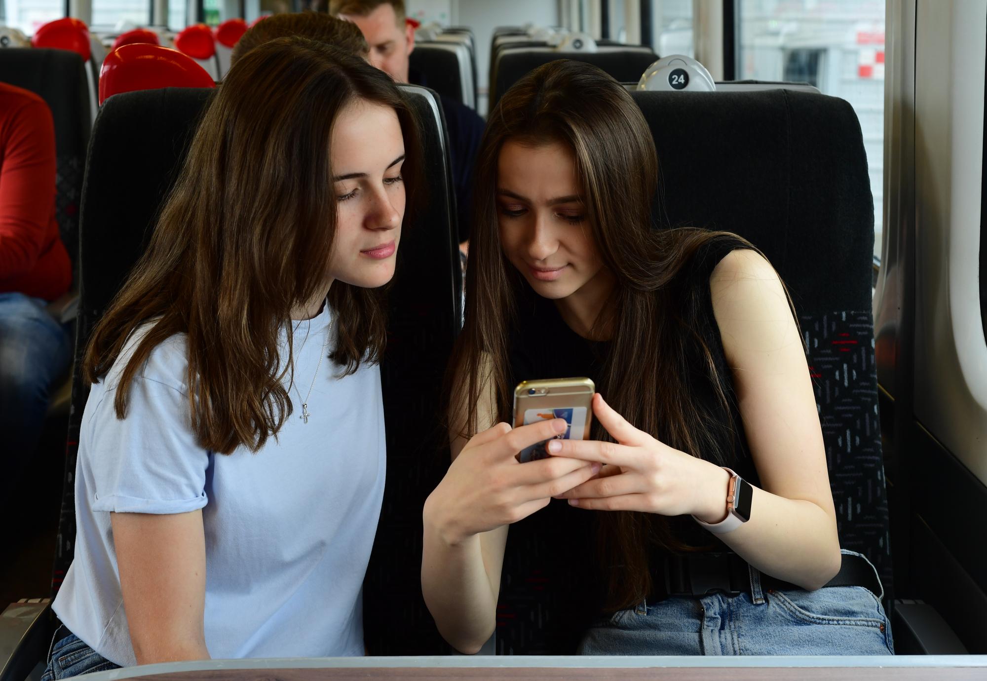 Passengers using a mobile phone on a train service, via TfW 