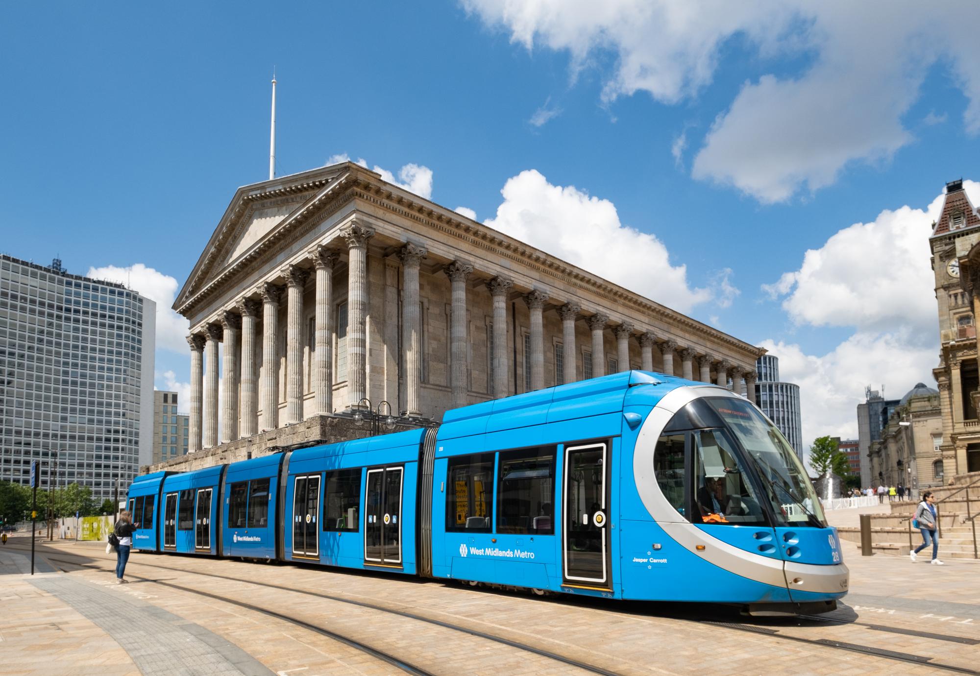 A blue West Midlands Metro tram at in front of Town Hall in Victoria Square, Birmingham, England, UK. Via Istock 