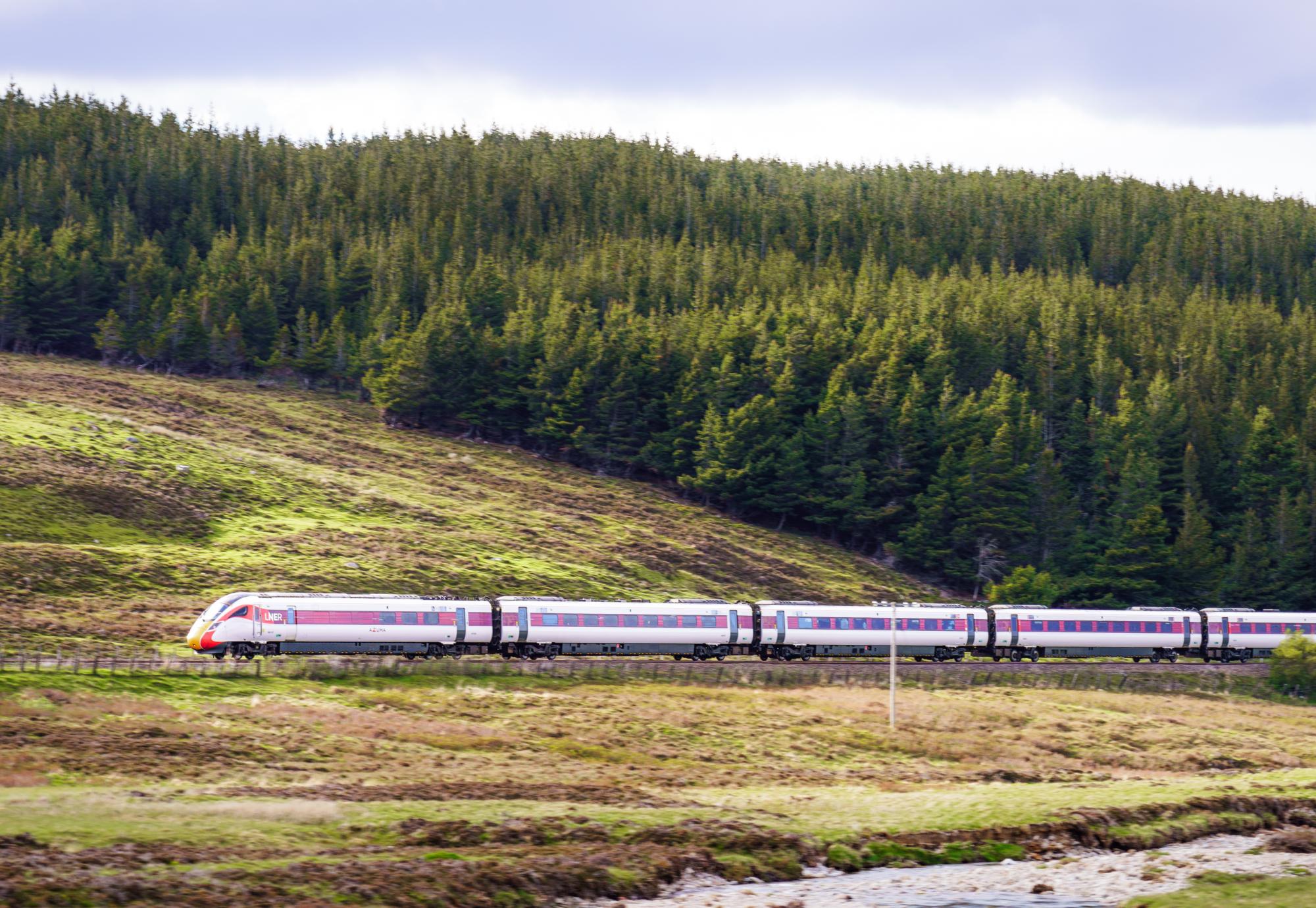 Side view of an LNER Azuma high speed train travelling at speed along a hillside in the Scottish Highlands