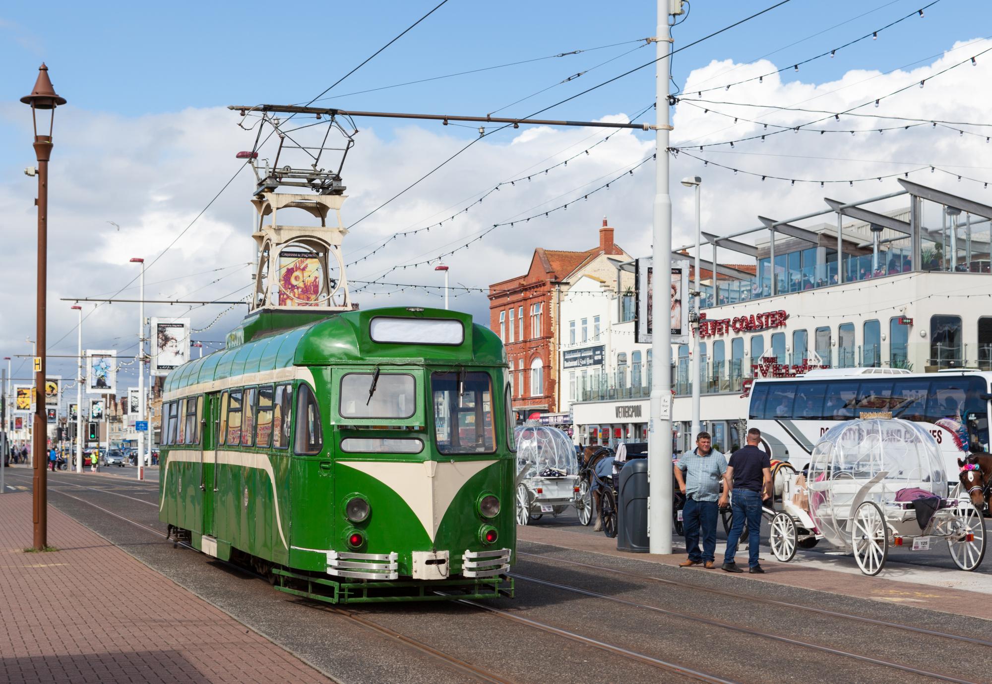 A green heritage tram on the promenade in Blackpool