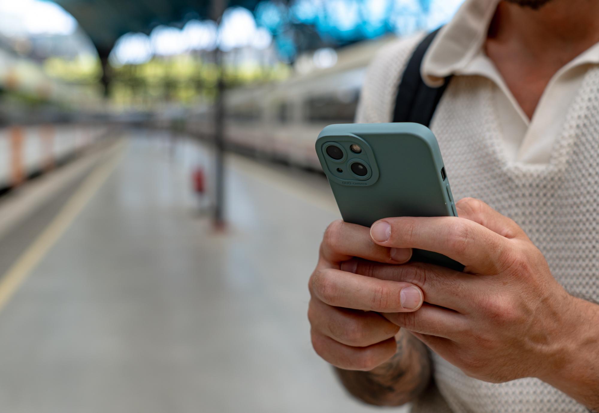 Man using a smart phone at a railway station