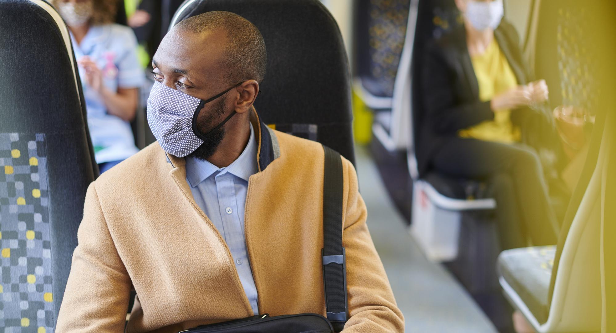 Train passenger sat in a seat wearing a face mask