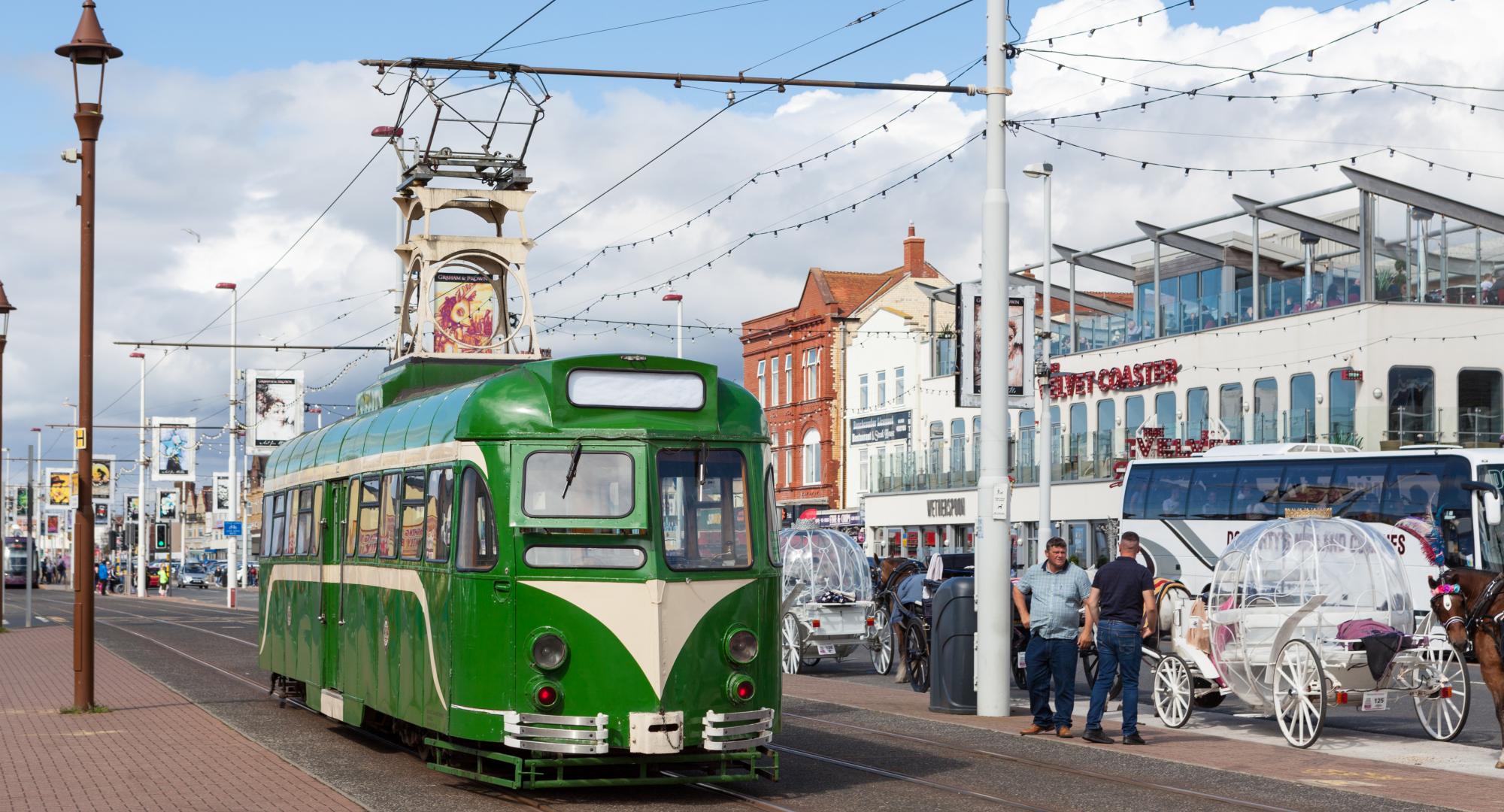 A green heritage tram on the promenade in Blackpool