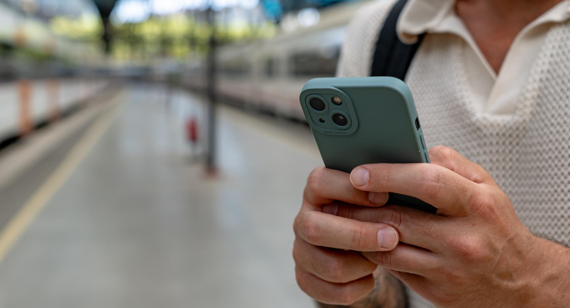 Man using a smart phone at a railway station