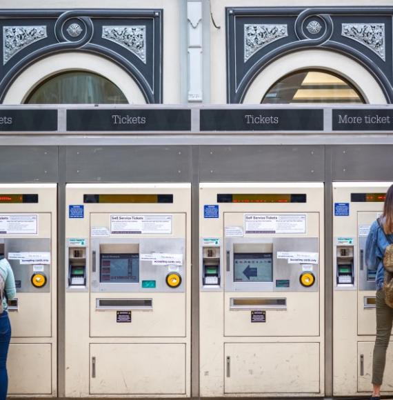 Two people buying train tickets 