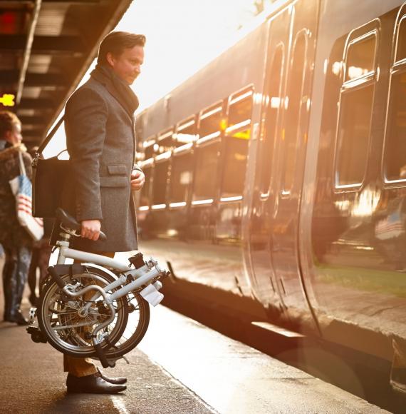 Businessman with a fold up bike at a train station