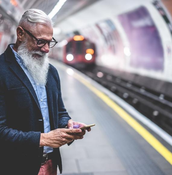 Male rail passenger at a station using a smartphone