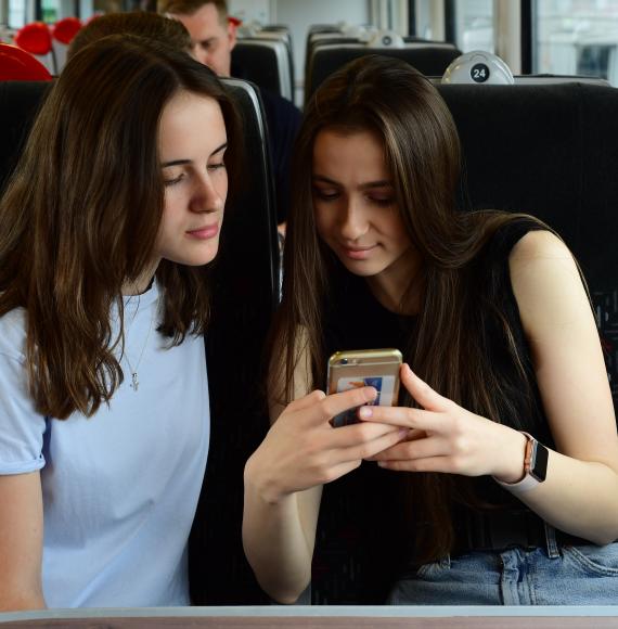 Passengers using a mobile phone on a train service, via TfW 