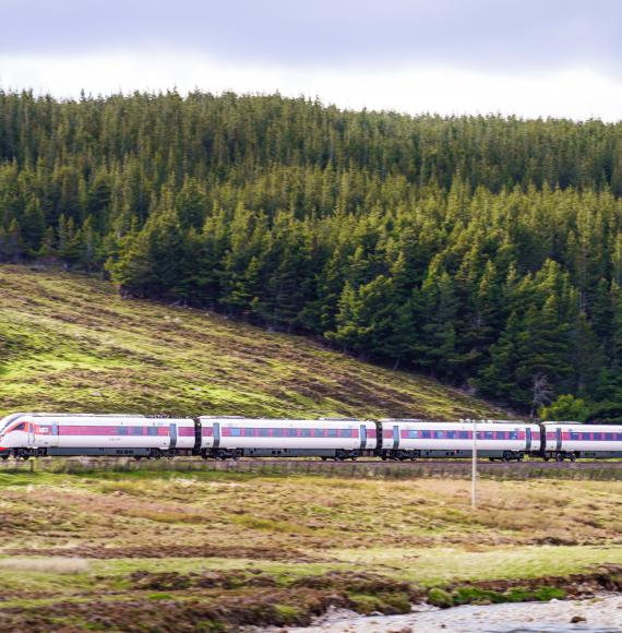 Side view of an LNER Azuma high speed train travelling at speed along a hillside in the Scottish Highlands
